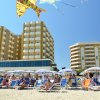 Spiaggia affollata, edifici alti sullo sfondo.