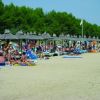 Persone distese su una spiaggia con ombrelloni di paglia.