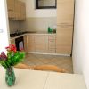 Cucina moderna con mobili in legno chiaro e fiori sul tavolo.