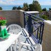 Balcone con tavolo apparecchiato, vista mare e alberi.