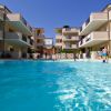 Complesso residenziale con piscina centrale, persone in acqua.