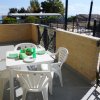 Tavolo bianco con sedie su terrazza soleggiata.