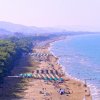 Spiaggia affollata con ombrelloni e mare calmo.