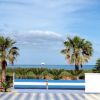 Vista sul mare e palme da una terrazza con panchine.