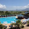 Una piscina con ombrelloni e lettini, circondata da montagne.