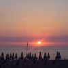 Tramonto sul mare con ombrelloni in silhouette.