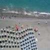 Spiaggia con ombrelloni bianchi visti dall'alto.