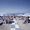 Persone su lettini sotto ombrelloni in spiaggia.