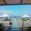 Spiaggia con ombrelloni bianchi e passerella a strisce.
