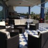 Terrazza con sedie e tavolini bianchi e marroni su pavimento a scacchi blu e bianchi.