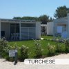 Due bungalow bianchi con giardino e sedie fuori.