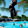 Persona salta felice vicino a una piscina.