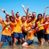 Gruppo allegro in magliette arancioni al mare.