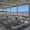 Tavoli all'aperto su una terrazza vista mare con ombrelloni arancioni.