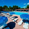 Piscina con ombrelloni blu e lettini bianchi.