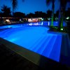 Piscina illuminata di notte, contornata da palme.