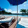 Lettini bianchi sotto ombrelloni blu vicino alla piscina.