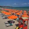 Spiaggia con ombrelloni arancioni e sdraio.