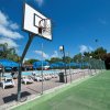 Campo da basket vicino a piscine con lettini e ombrelloni blu.