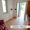 Soggiorno con angolo cottura e porta aperta verso l'esterno.