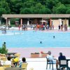 Piscina affollata con sedie e tavolini intorno.