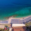 Spiaggia con ombrelloni blu e mare trasparente.