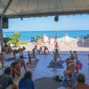 Persone fanno yoga in un portico vista mare.