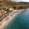 Spiaggia sabbiosa con ombrelloni, mare limpido.