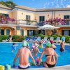 Persone in piscina davanti a un edificio giallo.