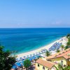 Spiaggia con mare blu e ombrelloni.