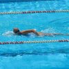 Persona che nuota in piscina con occhialini.