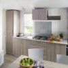 Cucina moderna in legno chiaro con tavolo e insalata.