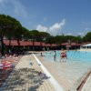 Piscina con bambini che giocano e pavimento bagnato.