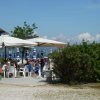 Persone sedute sotto ombrelloni bianchi vicino al mare.