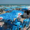 Tavoli e sedie blu con ombrelloni sulla spiaggia.
