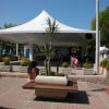 Gazebo bianco in piazza con panchina e alberi.