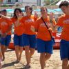 Gruppo di animatori in spiaggia con magliette arancioni.