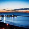 Tramonto su porto con luci e acqua calma.