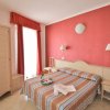 Camera con letto matrimoniale, parete rossa, e mobili chiari.