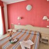 Letto matrimoniale con copriletto a righe, parete rossa, e comodini.