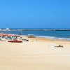 Spiaggia sabbiosa con ombrelloni colorati e mare calmo.